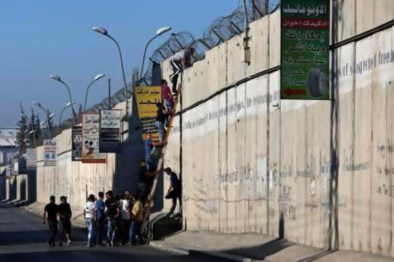Palestinian youths trying to reach Jerusalem climb over the controversial Israeli barrier in the West Bank village of Al Ram near Ramallah earlier this week.