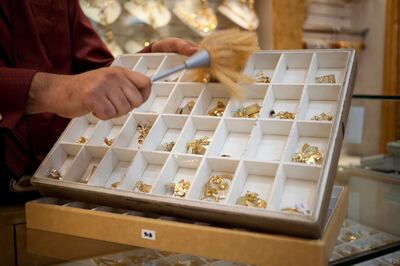 Dubai, United Arab Emirates - January 07 2013 - Kartik Satikunver, a salesman from Gujurat dusts gold jewelry at Kanz Jewels at the Gold Souk in Deira. (Razan Alzayani / The National)  