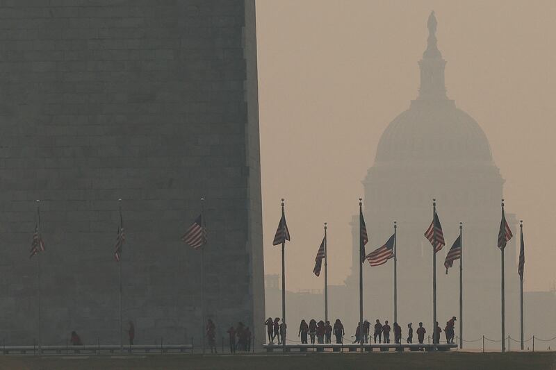 Tourists walk around the base of the Washington Monument as wildfire smoke casts a haze over the US Capitol. AFP