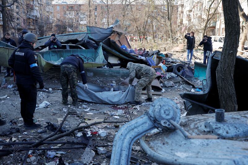 Rescue workers move the body of a victim killed when a shell hit a residential building in Kyiv on Friday. Reuters