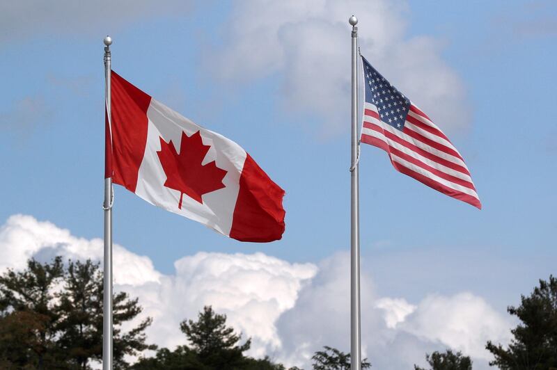 FILE PHOTO: A U.S. and a Canadian flag flutter at the Canada-United States border crossing at the Thousand Islands Bridge, which remains closed to non-essential traffic to combat the spread of the coronavirus disease (COVID-19) in Lansdowne, Ontario, Canada September 28, 2020.  REUTERS/Lars Hagberg/File Photo