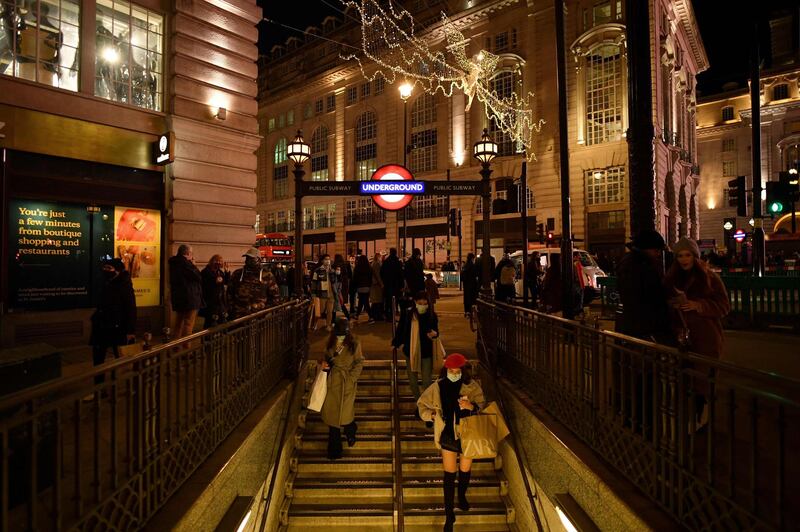 Christmas lights twinkle as shoppers make their way down the stairs to the Piccadilly underground station in London. AFP