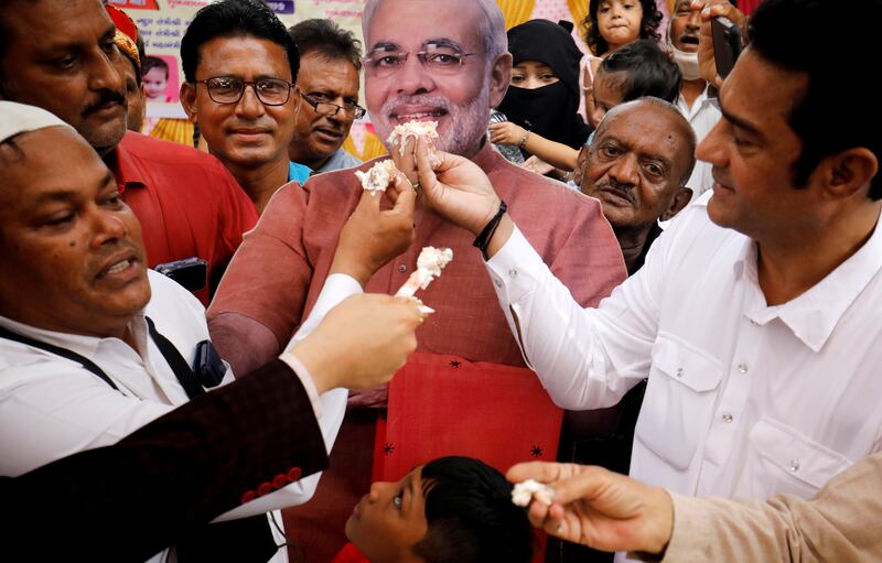 People offer pieces of a cake to a cut-out of Narendra Modi as they celebrate his birthday at an event in Ahmedabad. Reuters