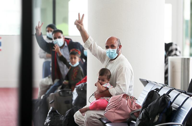 Passengers show the victory sign at Al Maktoum Airport in Dubai after arriving from Afghanistan. Pawan Singh / The National.