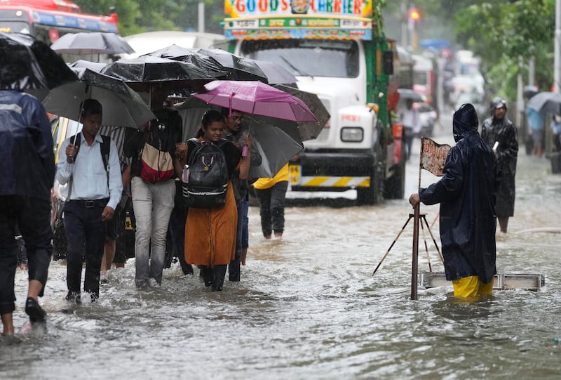 Many train stations remained inundated, forcing commuters to wade through knee-deep water.  AP Photo 