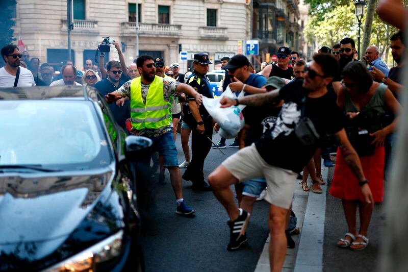 Protesting taxi drivers try to attack the vehicle of an app-based ride-service during a strike by cab drivers in Barcelona.  AFP / Pau Barrena