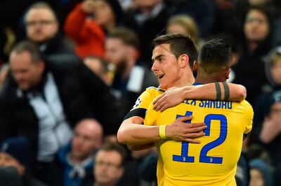 Juventus' Argentinian striker Paulo Dybala celebrates with Juventus' Brazilian defender Alex Sandro (R) after scoring their second goal during the UEFA Champions League round of sixteen second leg football match between Tottenham Hotspur and Juventus at Wembley Stadium in London, on March 7, 2018. / AFP PHOTO / Glyn KIRK
