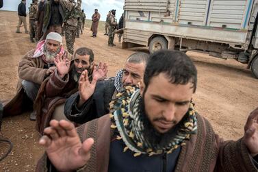 Men suspected of belonging to ISIS are screened by members of the Syrian Democratic Forces after fleeing from the last pocket of territory held by the group outside Baghouz. Campbell MacDiarmid / The National