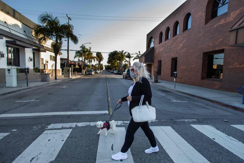 A woman crosses an empty street with her dog in Long Beach, California.  AFP