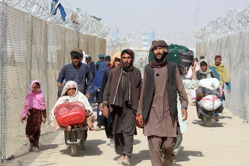 Afghan people walk inside a fenced corridor as they enter Pakistan at the Pakistan-Afghanistan border crossing point in Chaman. AFP