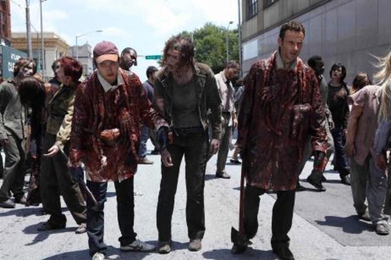 In this publicity image released by AMC, Steven Yeun, left, and Andrew Lincoln, right, try to blend in with the zombie population in a scene from "The Walking Dead." (AP Photo/AMC) *** Local Caption ***  YE_TV_Top_10_Shows_NYET202.jpg