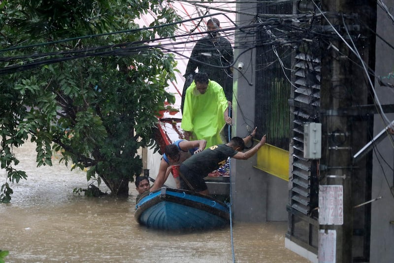 Residents trapped on their roofs board a small raft as they are evacuated as floods continue to rise in Marikina. AP Photo