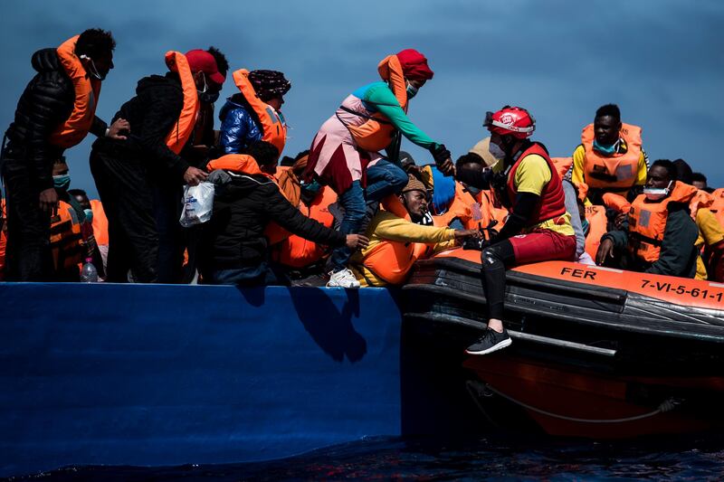 A lifeguard from the Spanish NGO Open Arms helps rescue a woman from a wooden boat filled with 84 migrants. Getty