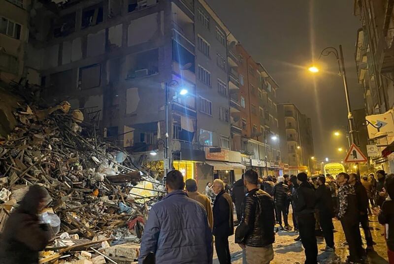 People gather around a collapsed building in Pazarcik, in Turkey's Kahramanmaras province. AP