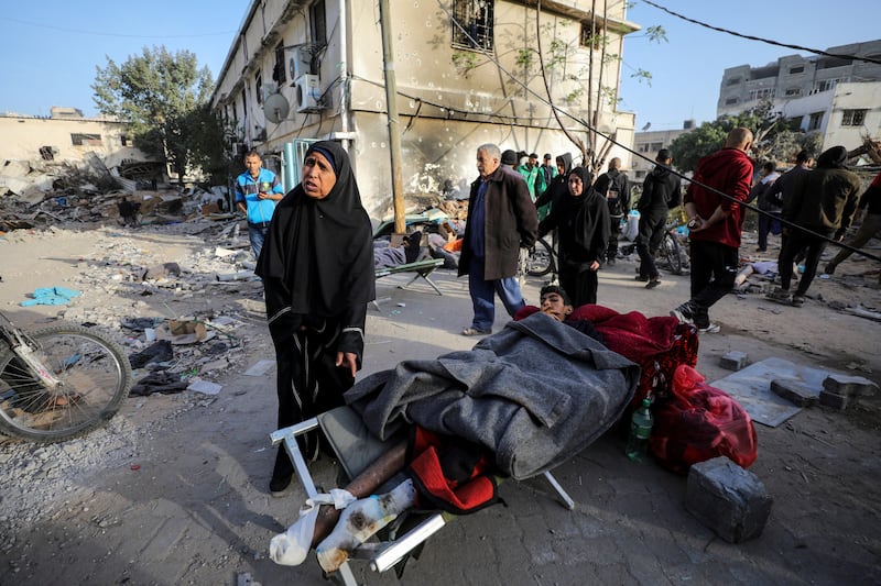 A woman stands next to a wounded Palestinian lying on a bed at Al Shifa Hospital after Israel's withdrawal. Reuters