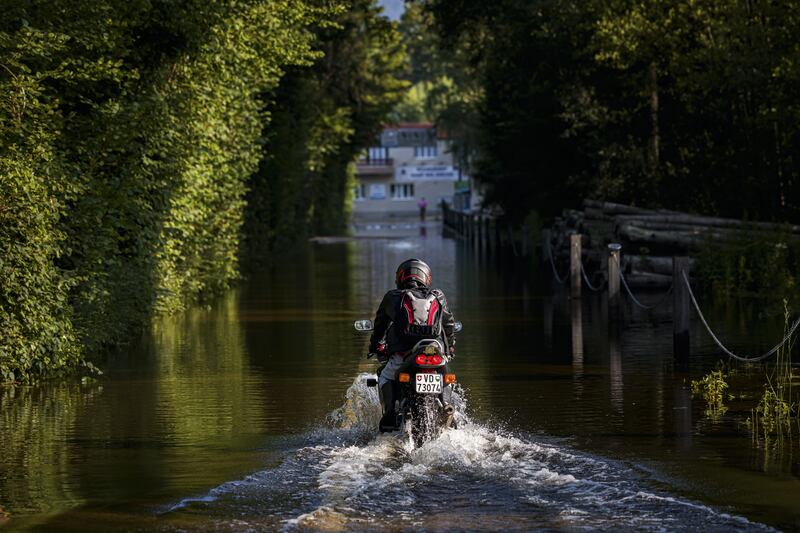 A man rides his motorbike through a flooded campsite in Cheseaux-Noreaz, Switzerland.