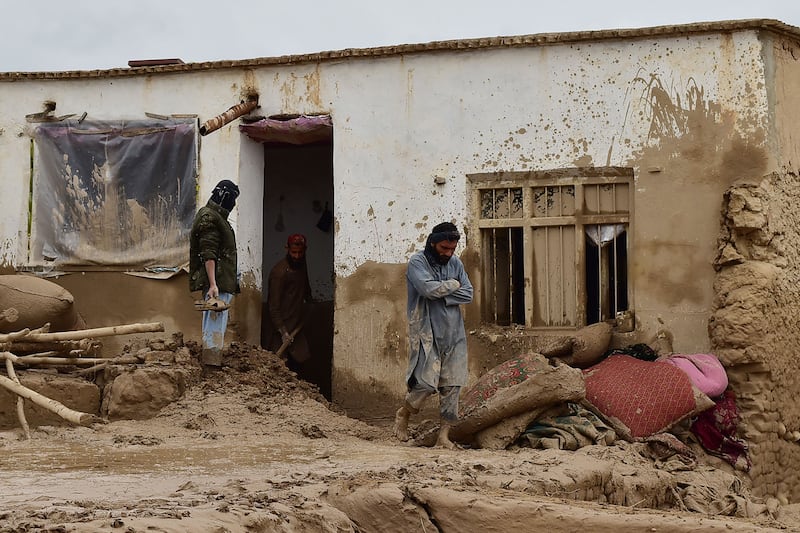 Afghan men clear debris and mud from a house in Laqiha village. AFP