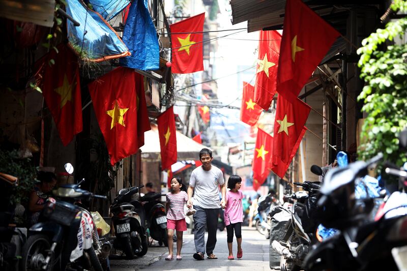 People walk under Vietnamese national flags at an alley in Hanoi, Vietnam.  Luong Thai Linh / EPA