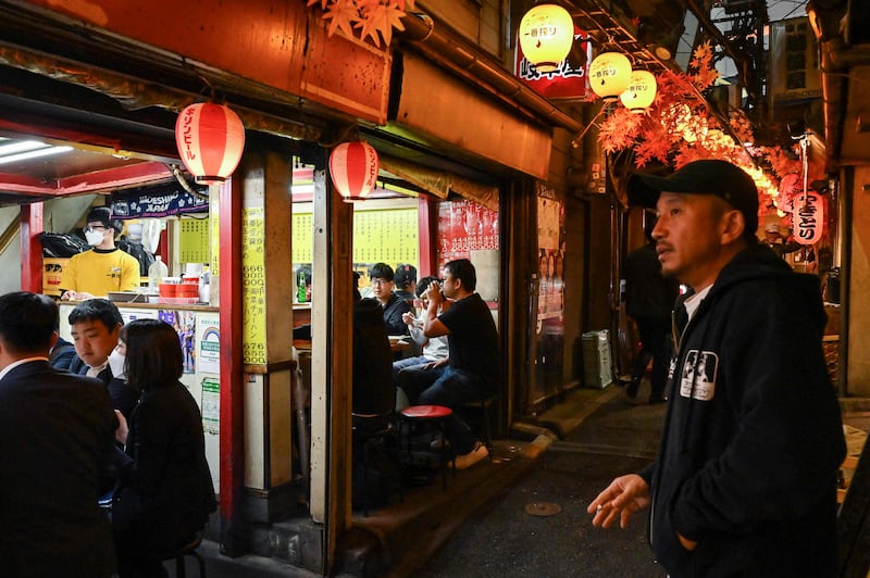Unmasked people have food and drinks outdoors in Omoide Yokocho in the Shinjuku area of Tokyo. AFP