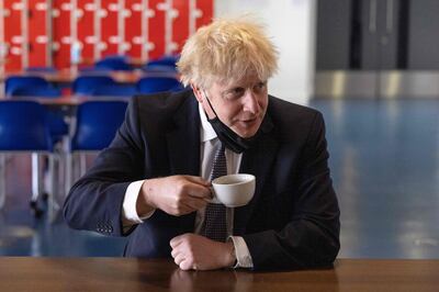 Britain's Prime Minister Boris Johnson, holds a cup of coffee as he speaks with pupils after taking part in a science lesson at King Solomon Academy in London, on April 29, 2021. / AFP / POOL / Dan Kitwood

