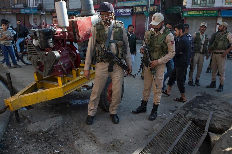 Indian policemen and locals inspect the site of an explosion in Srinagar, Indian controlled Kashmir, Saturday, Oct. 12, 2019. At least seven pedestrians were wounded on Saturday in Indian portion of Kashmir in a grenade explosion, according to authorities. (AP Photo/ Dar Yasin)