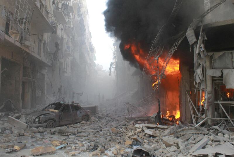 Debris cover a street and flames rise from a building following a reported air strike by Syrian government forces on March 7, 2014 during the Friday prayer in the Sukkari neighborhood of the northern city of Aleppo. More than 140,000 people have been killed in Syria since the start of a March 2011 uprising against the Assad family's 40-year rule. AFP PHOTO / BARAA AL-HALABI (Photo by BARAA AL-HALABI / AFP)