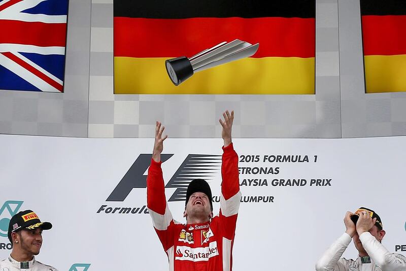 Vettel, centre, jumps throwing the trophy to the air next to second placed Lewis Hamilton, left, and third place Nico Rosberg. Fazry Ismail / EPA
