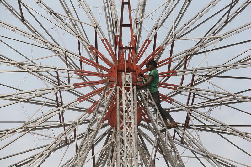 A man tightens the centre bolt of a Ferris wheel at a fair in Mumbai. Reuters