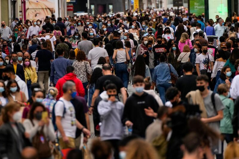 People wearing face masks walk along a commercial street in downtown Madrid, Spain. AP Photo