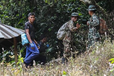 Two Thai birds nest collector, seen at left in civilian clothes are escorted by park rangers (R) in Khun Nam Nang Non Forest Park in the Mae Sai district of Chiang Rai province on July 5, 2018.

 A team of bird's nest collectors from southern Thailand put their generations-old rock climbing know-how to use on July 5 by scouring a mountainside for openings that could lead to 12 young footballers and their coach trapped inside a flooded cave. / AFP / THAI NEWS PIX / Krit PHROMSAKLA NA SAKOLNAKORN
