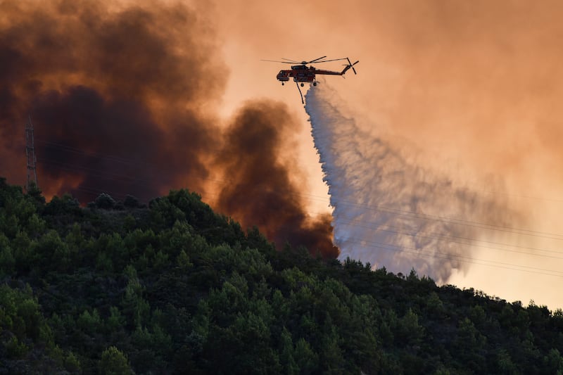 A firefighting helicopter drops water near the village of Krestena in Greece. AP