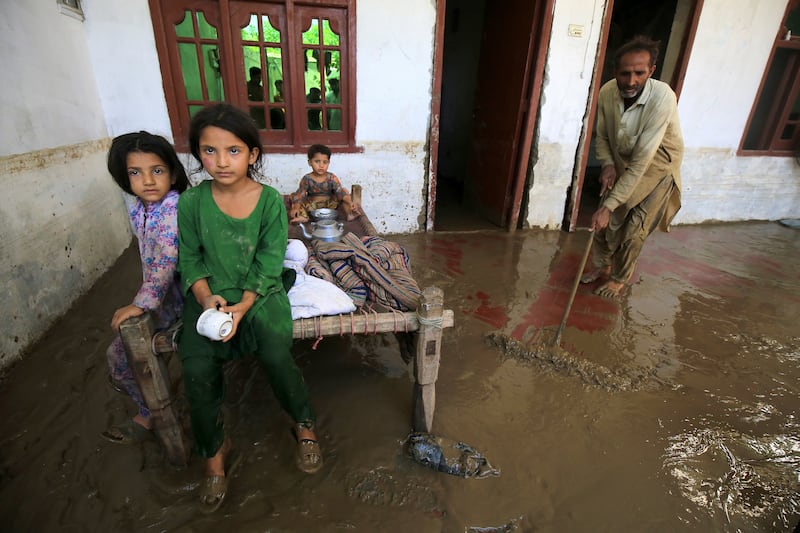A householder sweeps muddy water out of his home in Charsadda district, Khyber Pakhtunkhwa province. EPA