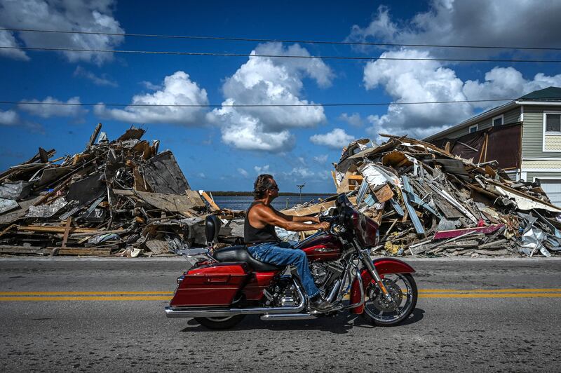 A motorcyclist passes debris piled up from a home destroyed by Hurricane Ian on Matlacha Island in Florida on the eve of the midterm elections.  AFP