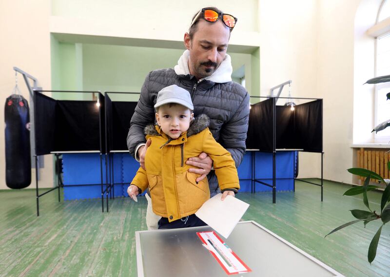 A voter with a child prepares to cast his ballot. AFP