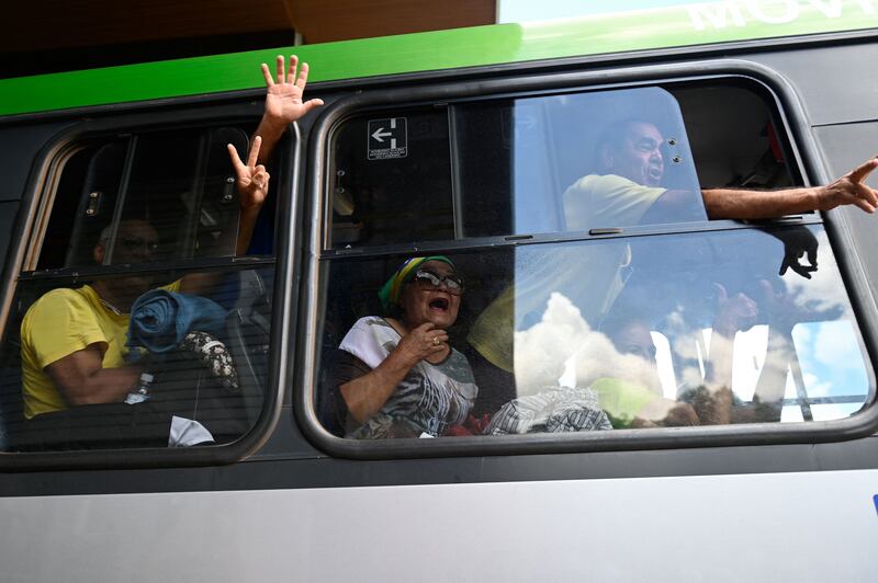 Bolsonaro supporters who were arrested following Sunday's attacks gesture from inside a bus while leaving Federal Police headquarters in Brasilia. AFP