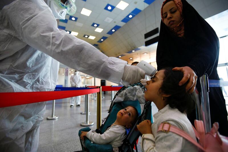 A medical staff member in protective gear checks the temperature of a girl amid concerns over the coronavirus (COVID-19) spread, at Najaf airport in the holy city of Najaf upon his arrival from Iran, Iraq. REUTERS