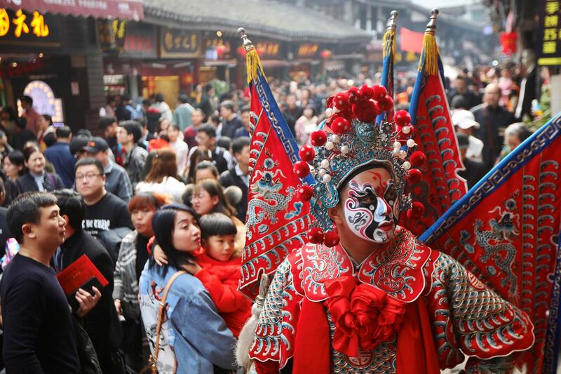 A man dressed in Peking opera costume attracts customers on the third day of Chinese Lunar New Year of the Pig, at the ancient town of Ciqikou in Chongqing, China.  Reuters