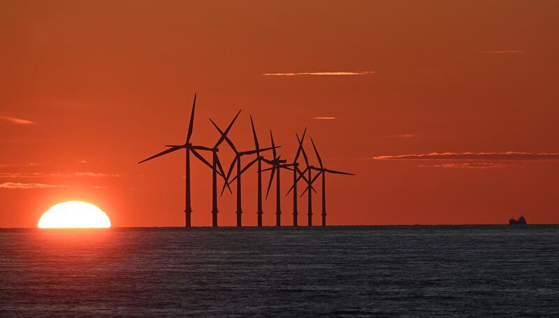 TOPSHOT - The sun sets behind the Burbo Bank Offshore Wind Farm in Liverpool Bay in the Irish Sea in north west England on May 26, 2021. / AFP / Paul ELLIS
