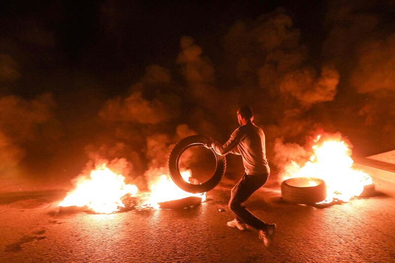 A demonstrator sets a tire aflame while cutting off a road in the centre of Lebanon's capital Beirut late. AFP
