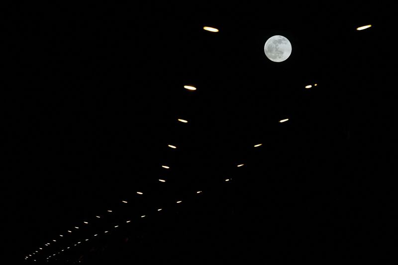 The moon is seen behind street lights on May 5, 2023 in Ibiza, Spain. AFP 