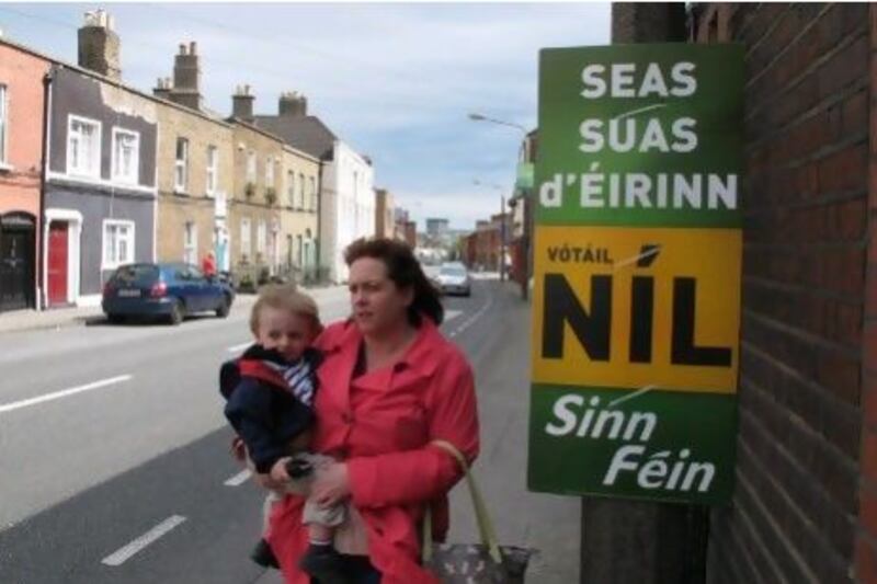 A mother and child in Dublin walk past a poster urging a "no" vote in the treaty poll. It reads in Gaelic: "Stand up for Ireland. Vote no.''