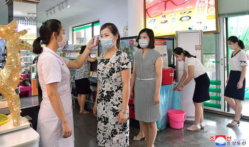 An employee of Pyongyang Glasses Shop takes the temperature of customers as quarantine measures of the Covid-19 coronavirus infection. KCNA / AFP