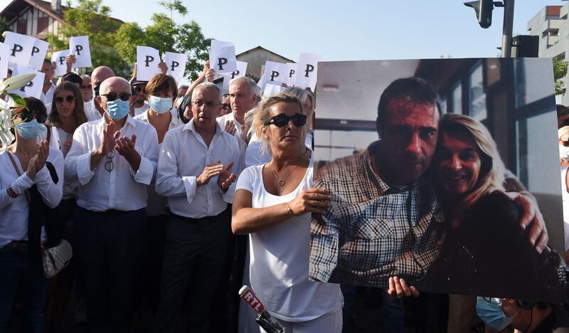 Veronique Monguillot, wife of bus driver Philippe Monguillot, declared brain dead after being attacked for refusing to let aboard a group of people who were not wearing face masks, holds a picture of her husband during a white march in Bayonne, southwestern France, on July 8, 2020. Four men set upon 59-year-old Philippe Monguillot in the southwestern town of Bayonne on July 5 after he asked three of them to wear masks and tried to check another man's ticket. The other two men have been charged with non-assistance to a person in danger and one has also been charged with attempting to hide a suspect, the local prosecutor's office said. / AFP / GAIZKA IROZ
