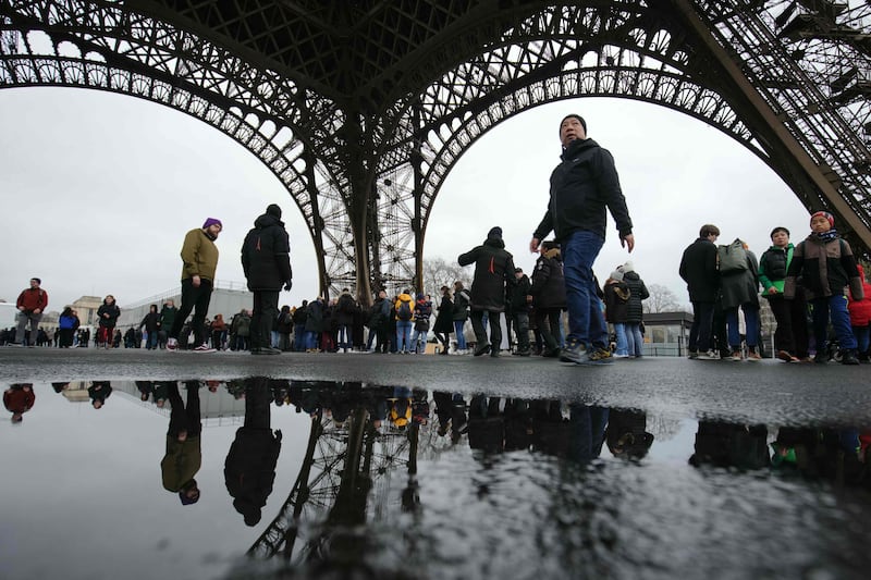 Visitors queue under the Eiffel Tower to enter, on the day of its reopening after a strike, in Paris. AFP