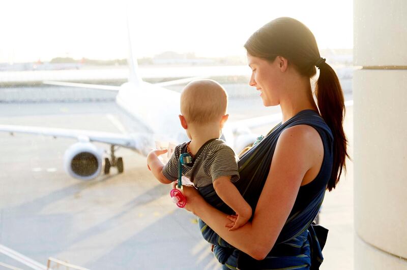 Mom with baby looking at plane at an airport. Getty Images