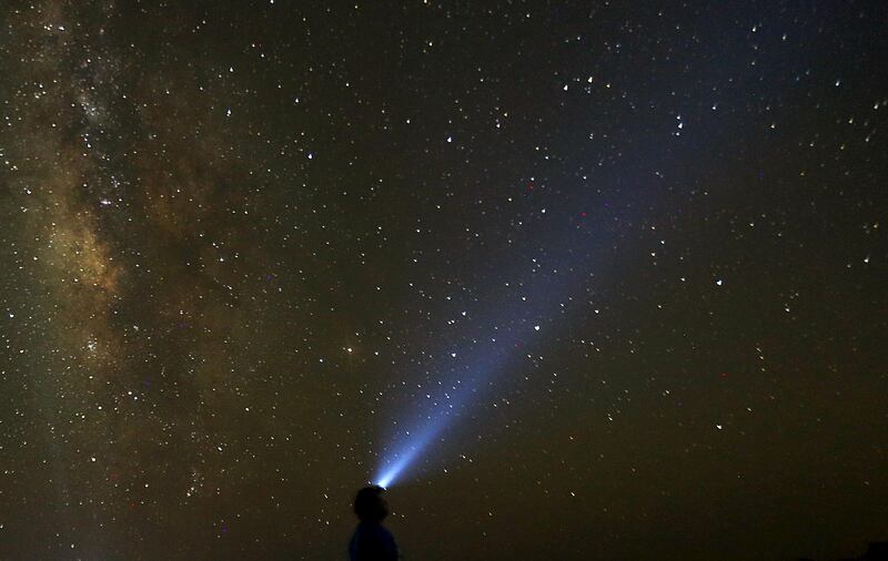 A man used a light on his head to monitor the Milky Way is seen in the night sky around camp in the natural reserve area of Wadi Al-Hitan, or the Valley of the Whales, at the desert of Al Fayoum Governorate, southwest of Cairo, Egypt, August 12, 2015. Wadi Al-Hitan holds an impressive collection of fossils and bones, some of which date back over 40 million years. The entire site resembles an open-air museum with marked trails and itineraries that visitors can follow to admire the fossils and rock formations that extend over a vast area. Picture taken August 12, 2015. REUTERS/Amr Abdallah Dalsh - RTX1O8FC