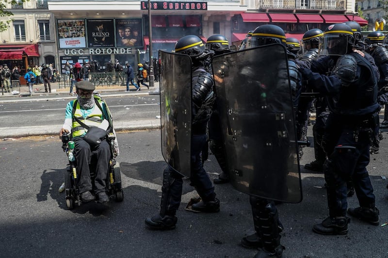 A protester in a wheelchair, wearing a yellow vest (gilet jaune) faces anti-riot police forces in the Montparnasse district of Paris, ahead of the start of the annual May Day (Labour Day) workers' demonstration in Paris on May 1, 2019.  France's zero-tolerance approach to protest violence will be tested on May 1,  when a heady mix of labour unionists, "yellow vest" demonstrators and hardline hooligans are expected to hit the streets on Labour Day. More than 7,400 police and gendarmes will be deployed across Paris with orders from the French President to take an "extremely firm stance" if faced with any violence, government spokeswoman said on April 30. / AFP / KENZO TRIBOUILLARD
