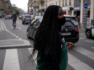 A woman wearing a protective face mask as a precaution against the coronavirus stands on a pedestrian crossing, in Paris, Thursday, Oct. 8, 2020. French authorities have placed the Paris region on maximum virus alert, banning festive gatherings and requiring all bars to close but allowing restaurants to remain open, as numbers of infections are rapidly increasing. (AP Photo/Thibault Camus)