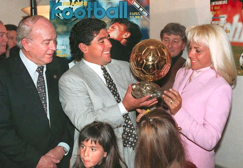 Argentinian soccer star Diego Maradona (C) hands the honorary "Ballon d'Or" (Golden Ball) award he received 03 January to his wife Claudia, as former soccer great Alfredo Di Stefano (L) looks on. In the foreground are Maradona's daughters Giannina (L) and Dalma (R). (Photo by PATRICK KOVARIK / AFP)