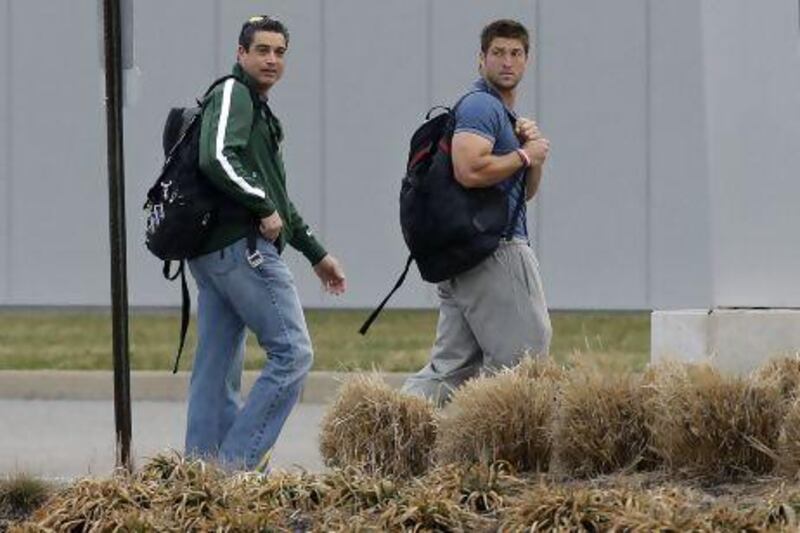 New York Jets quarterback and now free agent, Tim Tebow, right, walks away with the Jets assistant coach, Louis Aguiar. Mel Evans / AP Photo